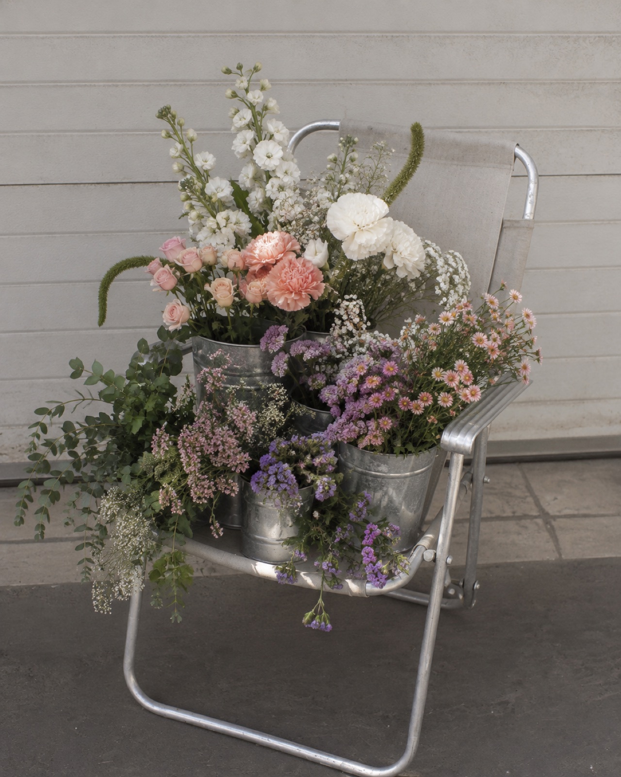Cubetas de flores frescas montadas sobre una silla plegable, como formato alterno al rack