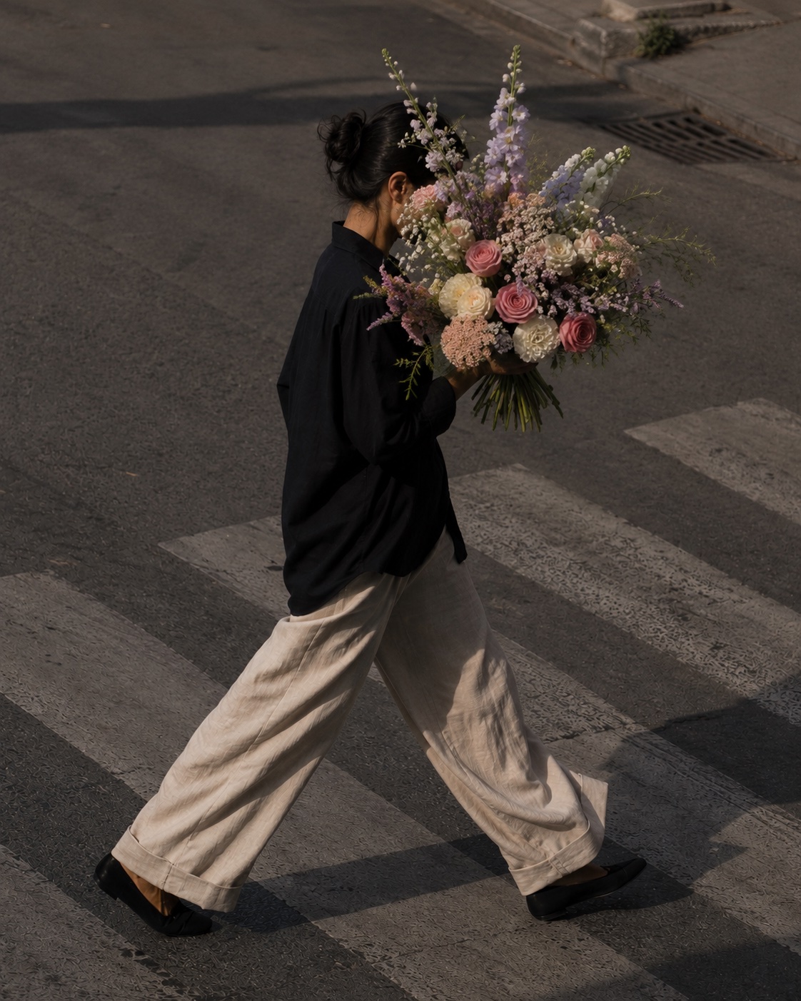 Persona cruzando una calle de CDMX con un ramo de flores grande que le tapa el rostro