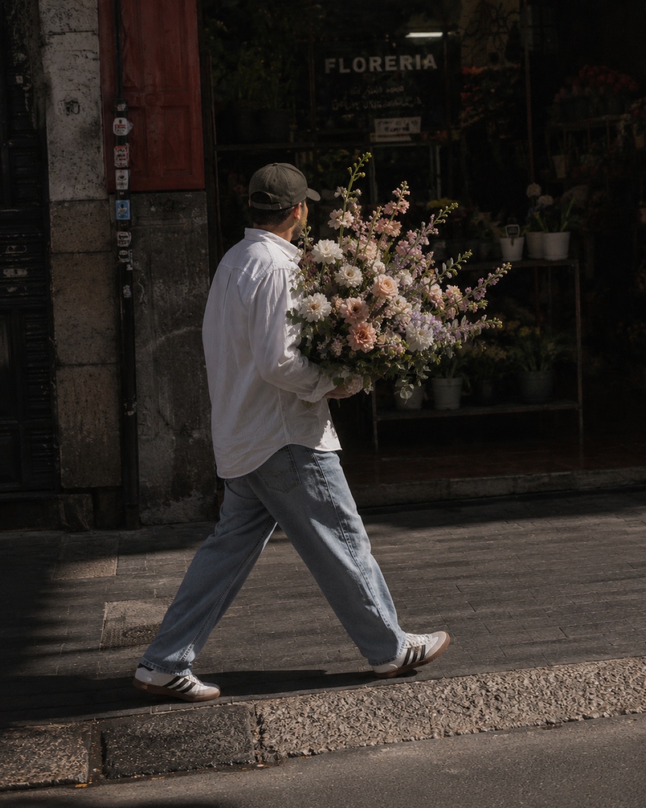 Persona caminando frente a una floristería en CDMX, cargando un ramo grande de flores